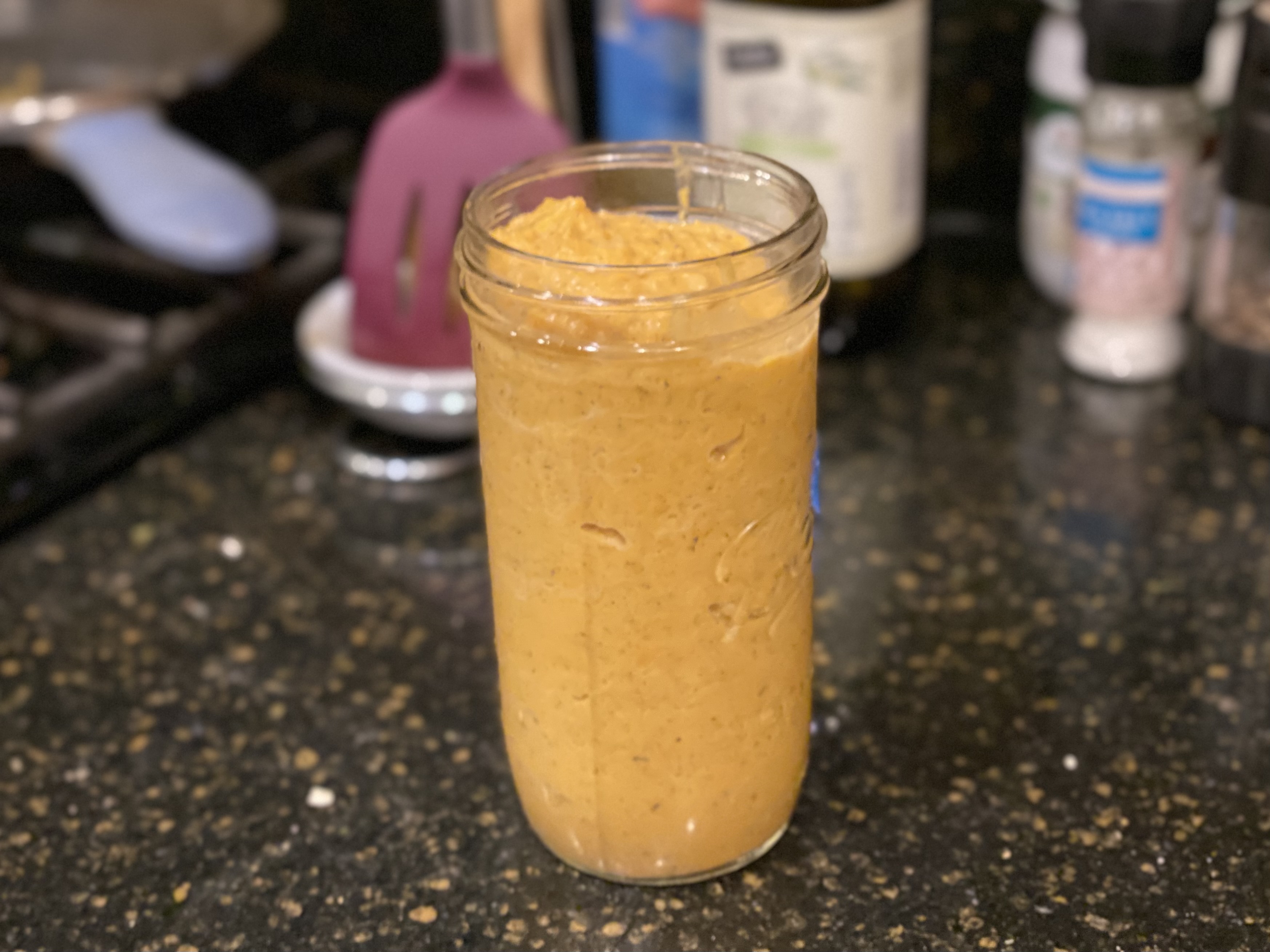 A tall mason jar filled with creamy orange butternut squash pasta sauce.